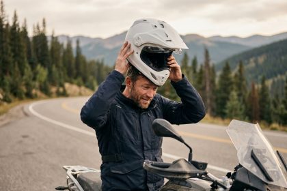 Motard retirant un casque intégral léger après un long trajet sur route de montagne