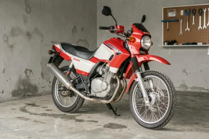 Honda XLV750R garée dans un garage, vue trois-quarts avant mettant en valeur le design double-sport et les équipements d'origine
