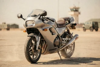 Moto Kawasaki Ninja vintage garée sur une piste d'aérodrome militaire désertique, évoquant l'univers de Top Gun
