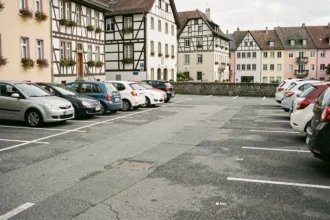 Parking à ciel ouvert en centre-ville de Colmar avec les maisons alsaciennes à colombages de la Petite Venise en arrière-plan