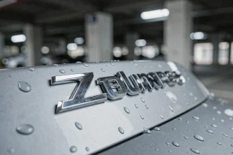 Gros plan sur un sigle chromé de voiture de luxe avec reflets métalliques et gouttes d'eau sur la carrosserie